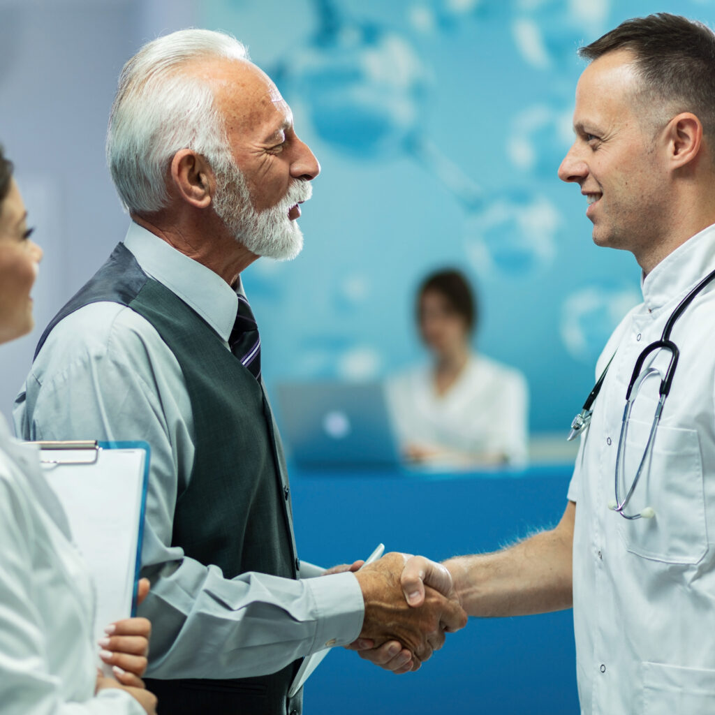 happy mature businessman shaking hands with doctor in the hospital.