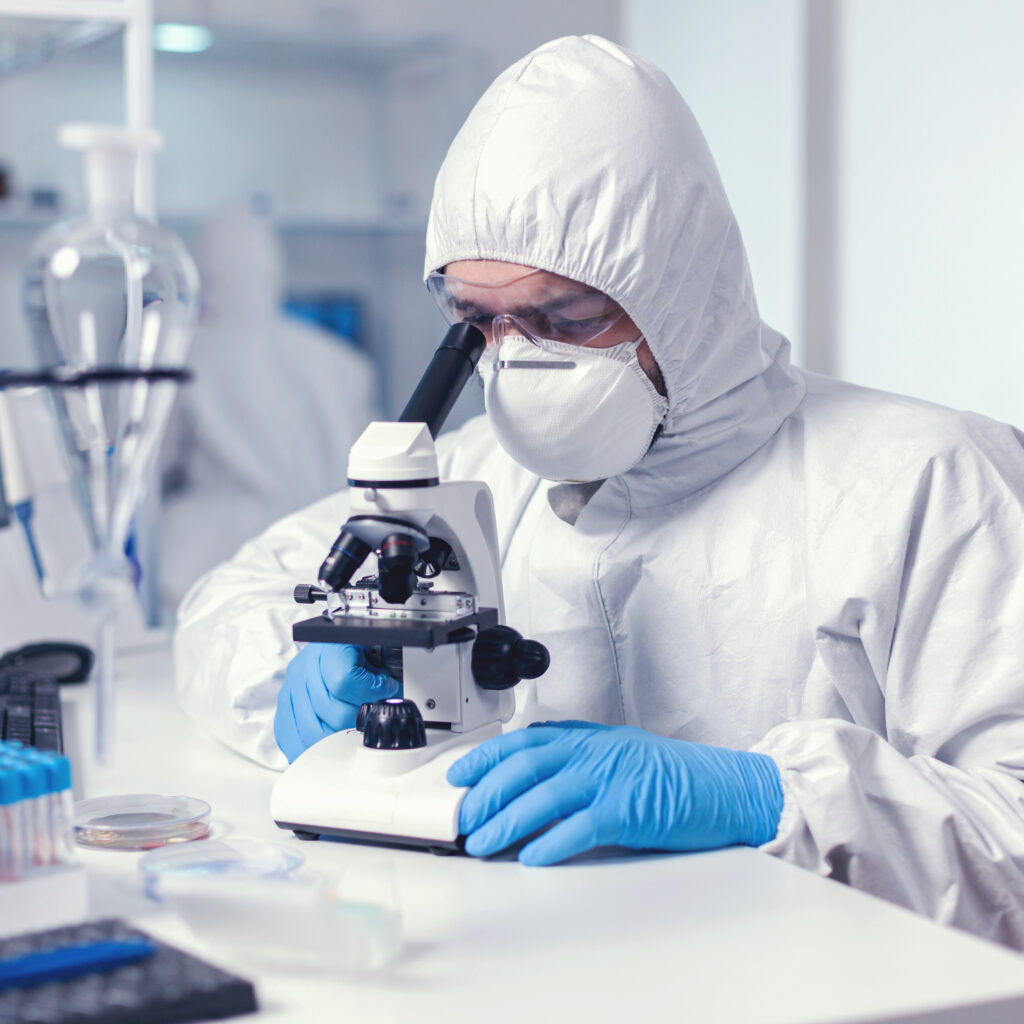 microbiologist with protection glasses using microscope